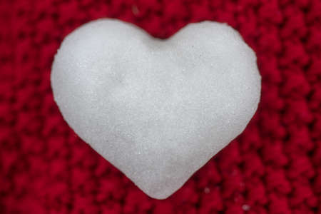 Knitted red background with heart of snow. Love winter. Valentine day background.の写真素材