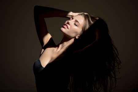 Portrait of elegant woman with light on a black background. Sensual girl with art shadow light. Beautiful female face in the darkness.の写真素材