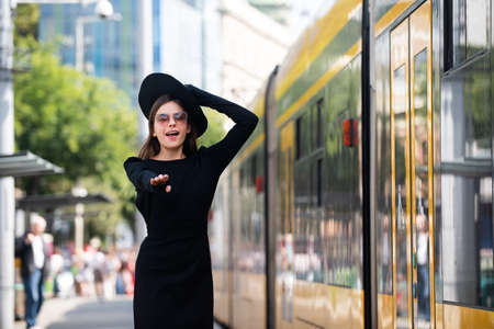 Beautiful young woman running after trolleybus bus in the city street. Beautiful young fashion woman. Traveling in city.の写真素材