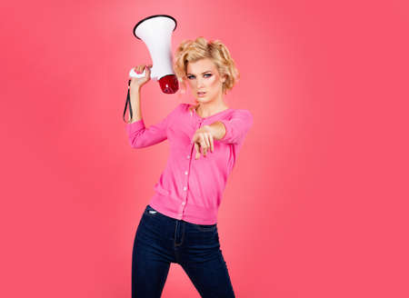 Megaphone and women. Portrait of pinup girl shouting. Young excited blonde fun woman pointing finger...