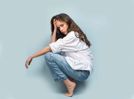 Fashion shot. Vogue young model in shirt and jeans posing at studio. Collection of fashion clothes.の写真素材