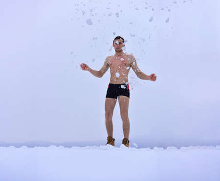 Naked man in the snow. Healthy cold swim. Winter fun, tempering procedures. Guy snow showers for the hardening of the body. Winter healthy lifestyle. Naked man takes a snow shower.の写真素材