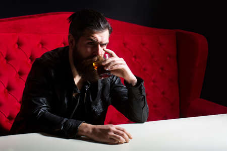 Bearded man drinking whisky, whiskey or cognac brandy. Hipster brutal man drinker alcoholic with alcoholism problem, alcohol abuse addiction concept. Drunken man behavior.の写真素材
