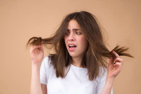 Sad girl looking at damaged hair, the hair loss problem. Isolated, copy space.の写真素材