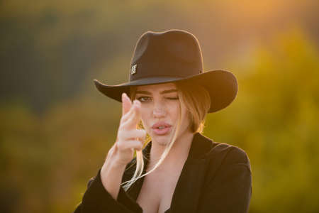 Female hand in gun gesture. Sensual portrait of elegant young woman outdoors. Beautiful fashionable girl. Soft sunny summer sunlight.の写真素材