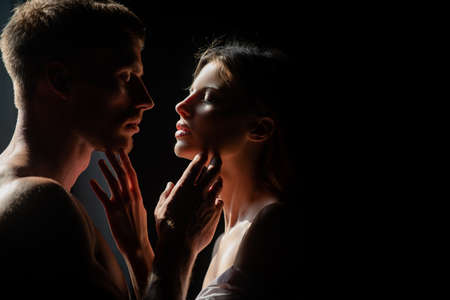 Beautiful loving couple posing on dark backgroung with night lights. Sensual portrait of a sexy couple embracing while dating. Young couple in love on black. The lovely coupl spends time together.の写真素材