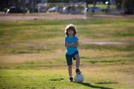 Childhood and sport. Football little champion. Boy child kicking football on the sports field during soccer match.の写真素材