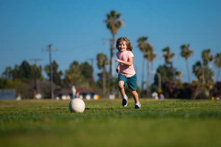 Kid playing soccer, happy child enjoying sports football game, kids activities, little soccer player. Kids play soccer game.の写真素材