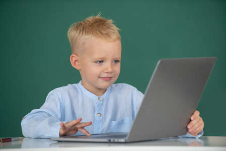 School boy learn lesson sitting at desk, studying online e-learning use internet. Genius child programming, computer training.の写真素材