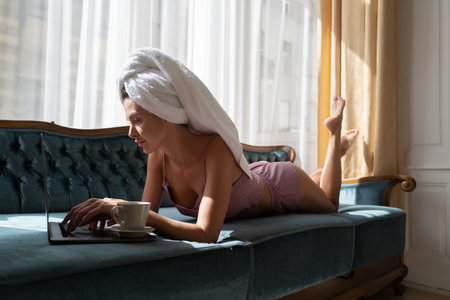 Girl resting and laying in cozy sofa bed in the luxury bedroom an easy morning. Sexy woman relaxing wearing bathrobes and towels in hotel room.の写真素材