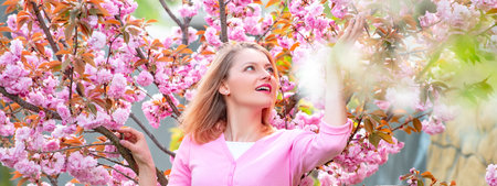 Spring couple in love, banner. Blonde woman enjoying a moment in blossoming sakura garden. Sunny...