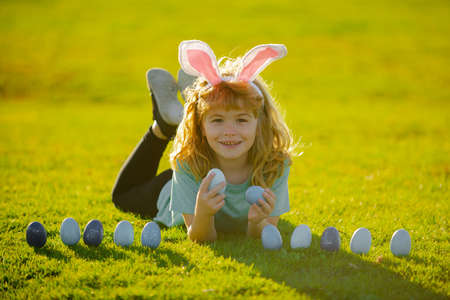 Kids on Easter egg hunt in garden. Children with colorful eggs in grass. Toddler boy play outdoors....