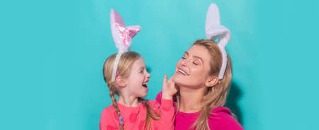 Happy mother and child daughter celebrating Easter. Cute little girl with funny face in bunny ears...