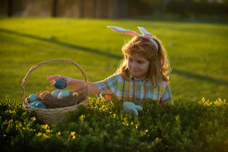 Kids boy hunting easter eggs in park. Child bunny boy with rabbit bunny ears.