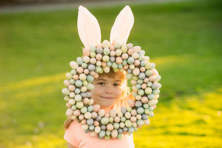 Child boy with easter eggs and bunny ears laying on grass. Funny kids face closeup.