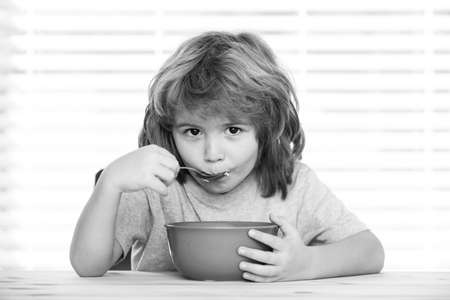 Caucasian toddler child boy eating healthy soup in the kitchen.の写真素材