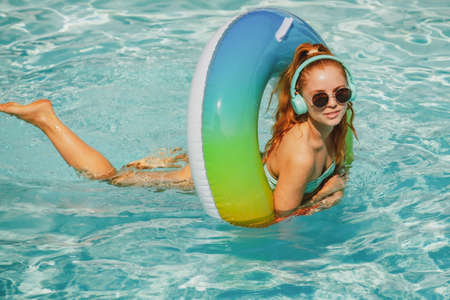 Summer Vacation. Enjoying suntan. Woman in swimsuit on swim ring in the swimming pool. Pool resort.の写真素材