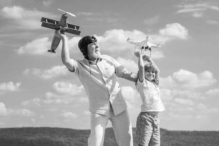 Child boy and grandfather with plane and quadcopter drone over blue sky and clouds background.