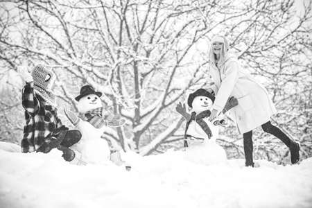 Hipster Girls friends playing with Snowman on snow Winter landscape. Christmas preparation - funny...
