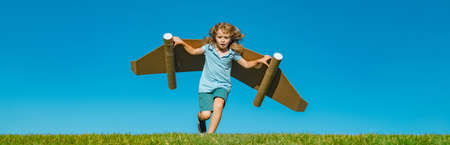 Banner with spring kids portrait. Happy child running with toy wings against summer sky background....