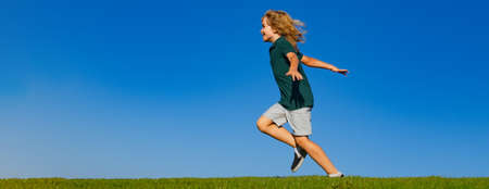 Banner with spring kids portrait. Sweet, happy child boy running playing on a grass in a park at a...