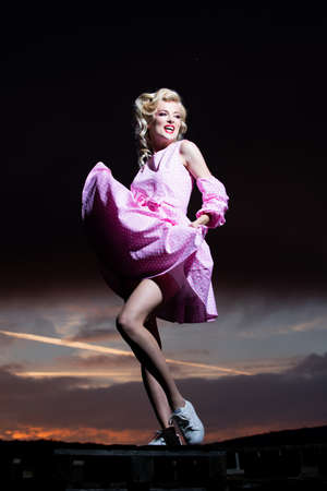 Woman in pink dress on sunset, monroe style. Female model in a fashion dress outdoor.