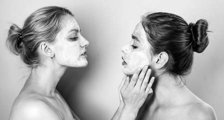 Healthy natural tender girls do beauty spa procedures with clay mud mask at face. Happy funny mood. Healthy and wellness concept. Women with bare shoulders do spa procedures.の写真素材