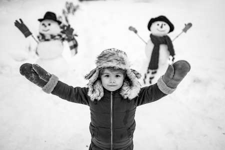 Winter scene with happy child on white snow background. Enjoying nature wintertime. Happy winter time. Snowman. Winter morning.の写真素材