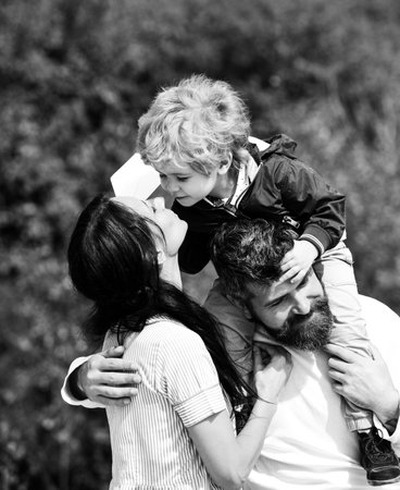 Portrait of happy father giving son piggyback ride on his shoulders, hug wife and looking up. Childhood. Father and his son child boy playing outdoors. Daddy, mommy and child son. Carefree.の写真素材
