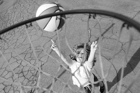 Cute little boy child in basketball uniform jumping with basket ball for shot. Happy child playing...