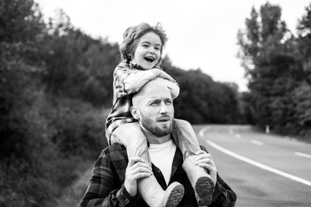 Father and son playing piggyback outdoor. Family walk in autumn background. Fatherhood.