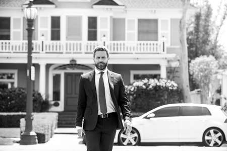 Real estate agent welcoming visitors near new house. Portrait of realtor man.