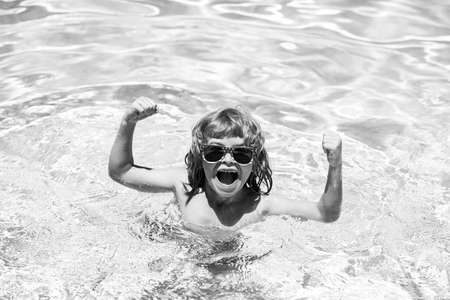 Excited cute little boy in sunglasses in pool in sunny day. Child relax in summer swimming pool.