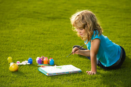 Kids painting drawing art. Child boy enjoying art and craft drawing in backyard or spring park. Children drawing draw with pencils outdoor.の写真素材