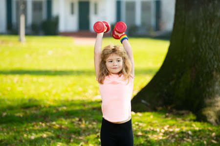 Fitness child. Sporty portrait kids. Fitness child with dumbbells in park. Gym workout. Child sportsman, childhood activity. Kids sport and fitness.の写真素材