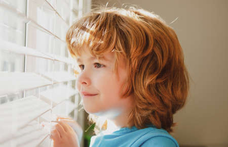 Protect yourself. Stay home in self isolation. COVID-19 Lockdown. Child looking through window. Qarantine concept. Coronavirus pandemic.の写真素材