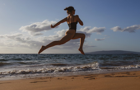 Woman run on the beach. Active sporty girl running along ocean surf by water pool to keep fit and health. Woman fitness, jogging workout and sport activity on summer holiday.の写真素材