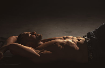 Sexy naked muscular man with sixpack abs lying in bed. Attractive young gay. Sexy handsome playboy outdoors. Handsome muscular man relaxing.の写真素材