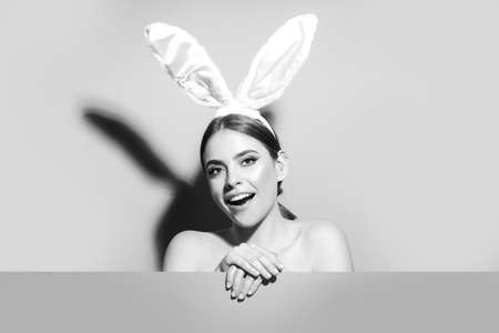 Easter bunny woman with rabbit ears. Beautiful young girl with on pink blank poster.の写真素材