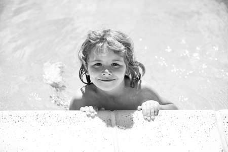 Cute child boy swim in swimming pool, summer water background with copy space. Funny kids face. Kid playing outdoors. Summer vacation and healthy lifestyle concept.の写真素材