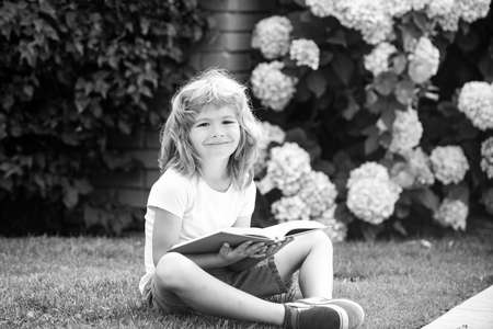 Child relax in the holiday. Kid read books on grass background. Learning concept.
