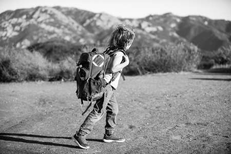 Kid with backpack hiking in scenic mountains. Local tourist goes on a local hike.