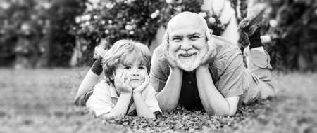 Child with Grandfather dreams in summer in nature. Portrait of happy senior and happy cute grandson....