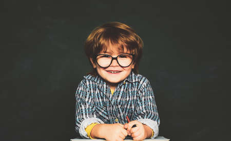Back to school and happy time. September 1. Blackboard copy space. Happy smiling pupils drawing at the desk. Great study achievement.の写真素材