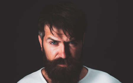 Head and shoulders portrait of a bearded middle-aged man looking at the camera over a black studio background with copy space.の写真素材