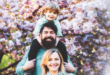 Parents giving child piggybacks in countryside. Mother father and son.の写真素材