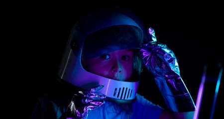 Child boy is dressed in an astronaut costume. Close up excited kids face on neon color.