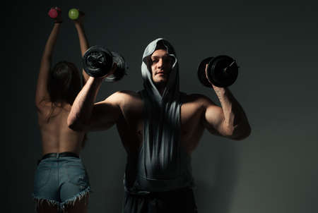 Sexy sport couple exercising with dumbbell. Slim and healthy sexy girl with strong muscular man workout.の写真素材