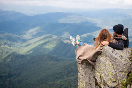 Romantic couple sit on rocks, romantic camping. Outdoor adventure with friends on nature. Romantic lovers on vacation camping. Panoramic mountains landscape.の写真素材