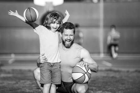 Cute boy with dad playing basketball. Dad and child spending time together. Father and son play outdoor.の写真素材